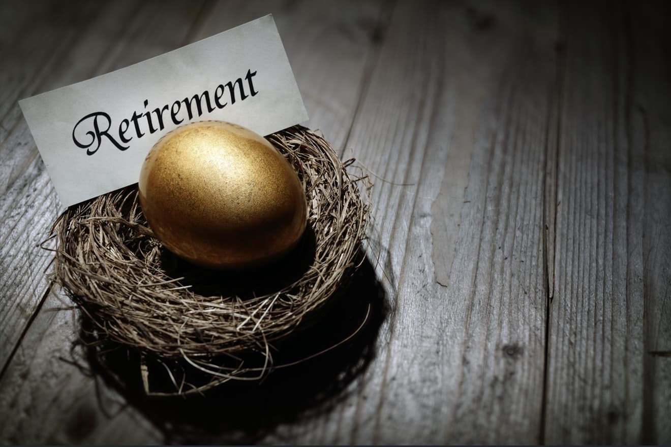 AB Retirement Nest Egg thats Gold with a Paper that says Retirement sitting on a wooden floor