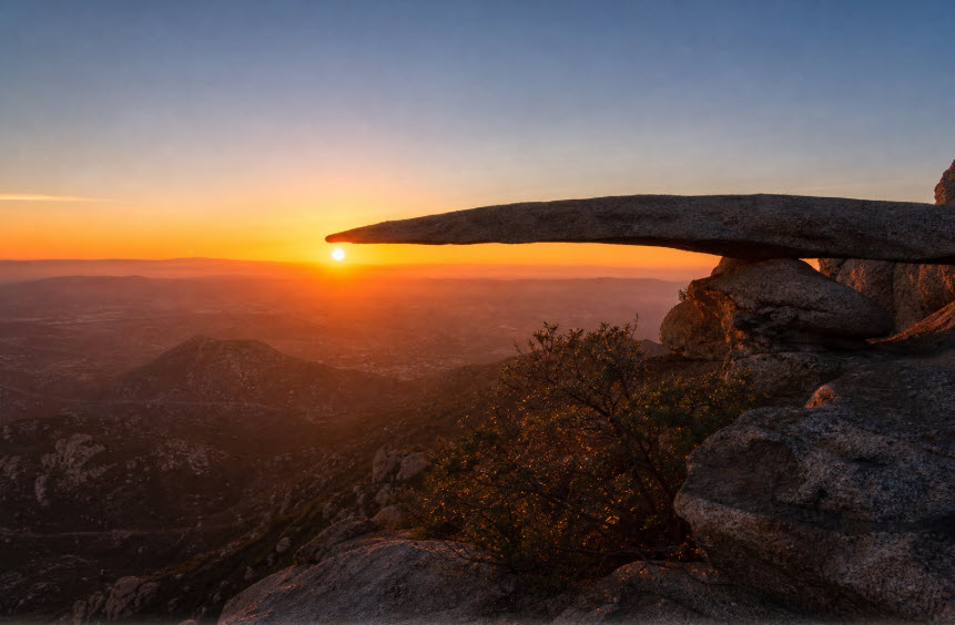 The sun rising behind Potato Chip Rock on Mount Woodson in San Diego County